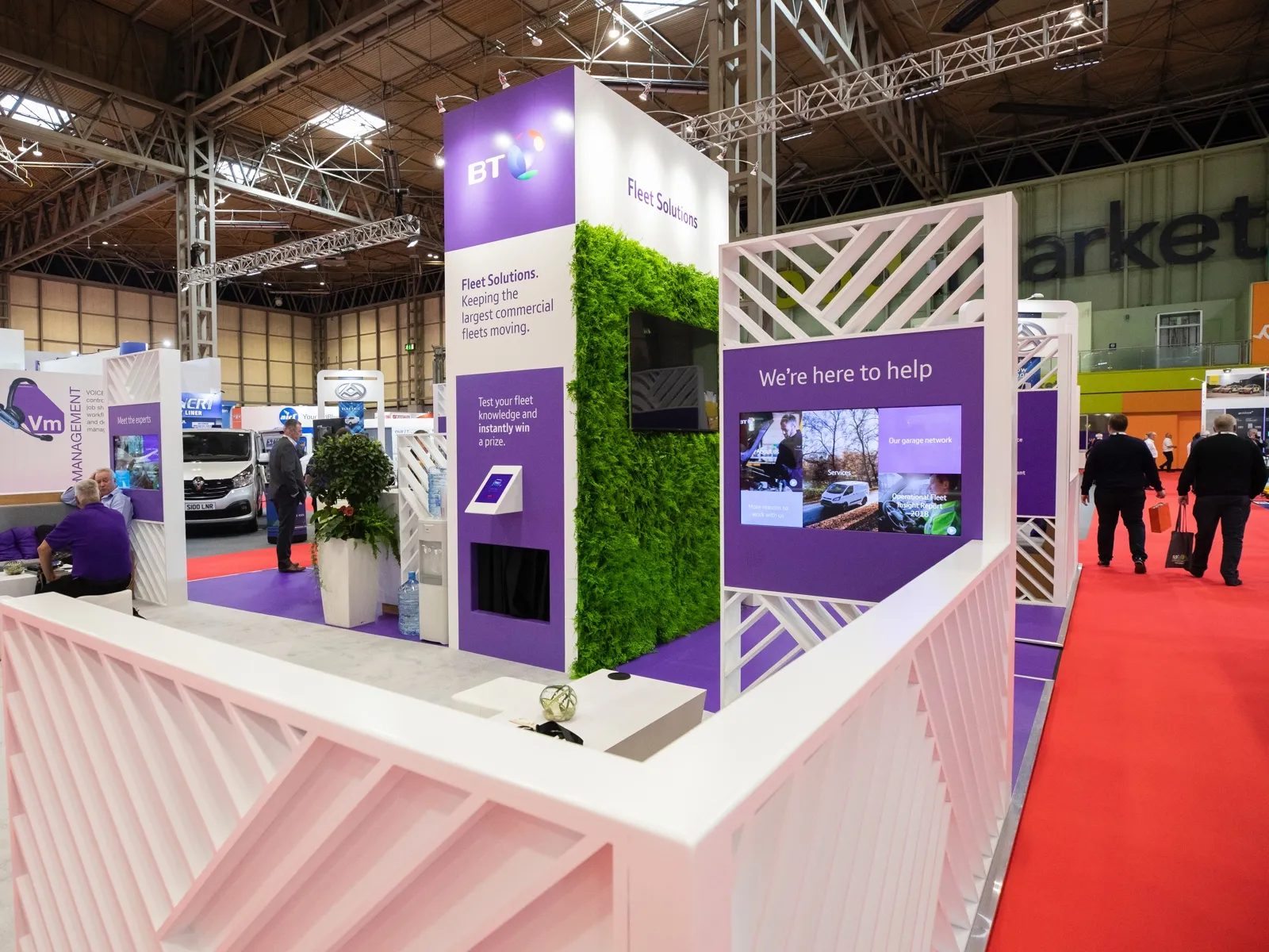 The BT Fleet Solutions stand at the event: purple BT branding, a living green wall and wall-mounted touchscreens.